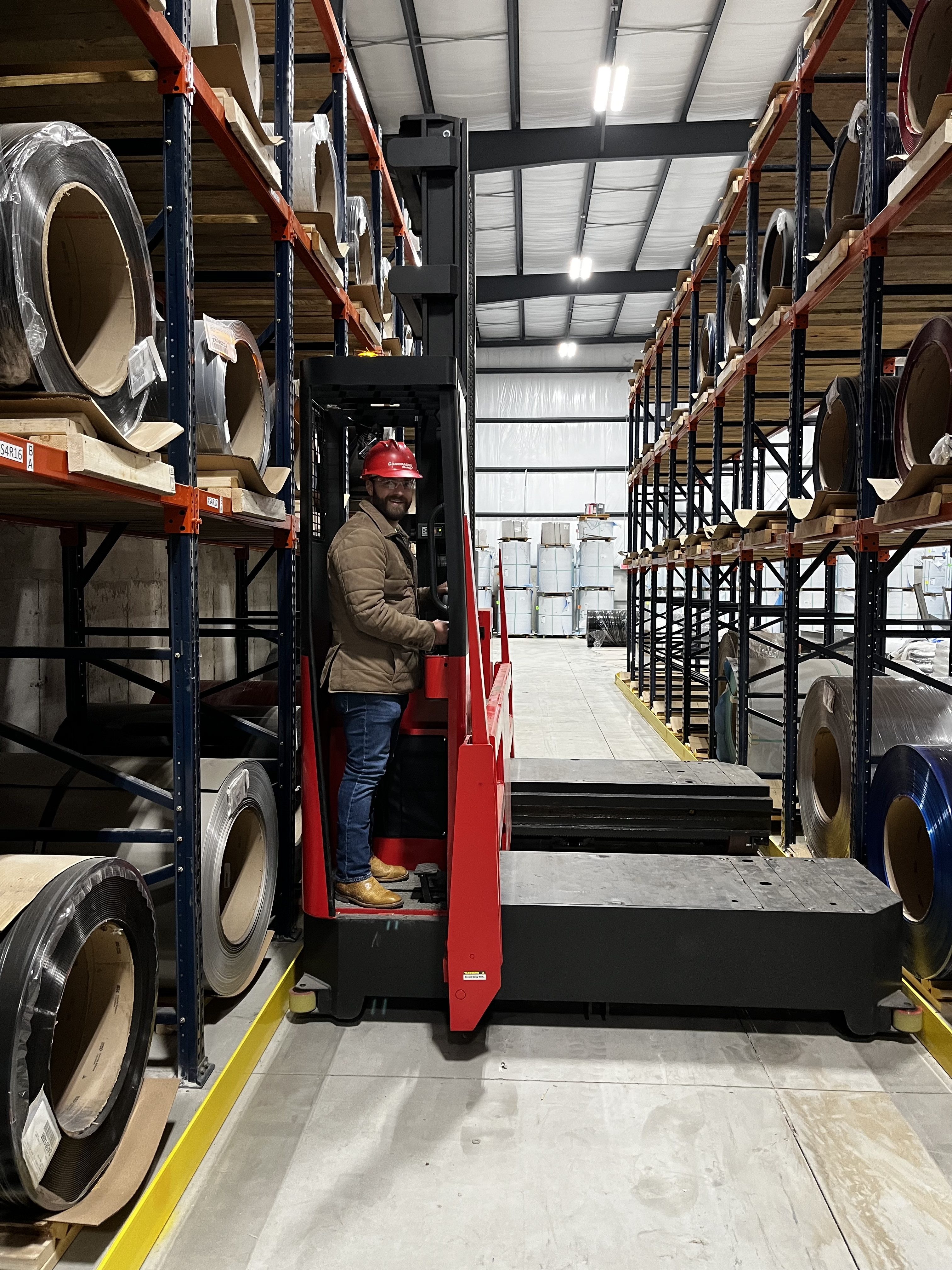 man on forklift in a warehouse surrounded by aluminum coil