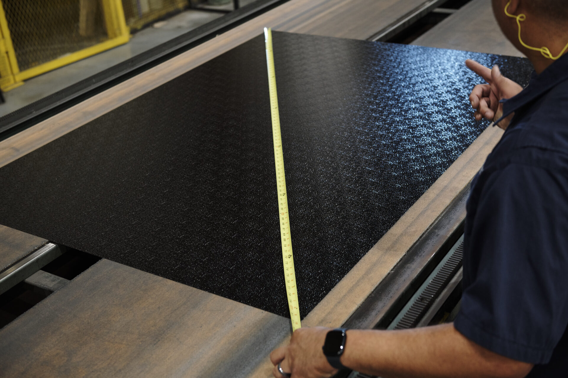 employee measuring a sheet of painted aluminum