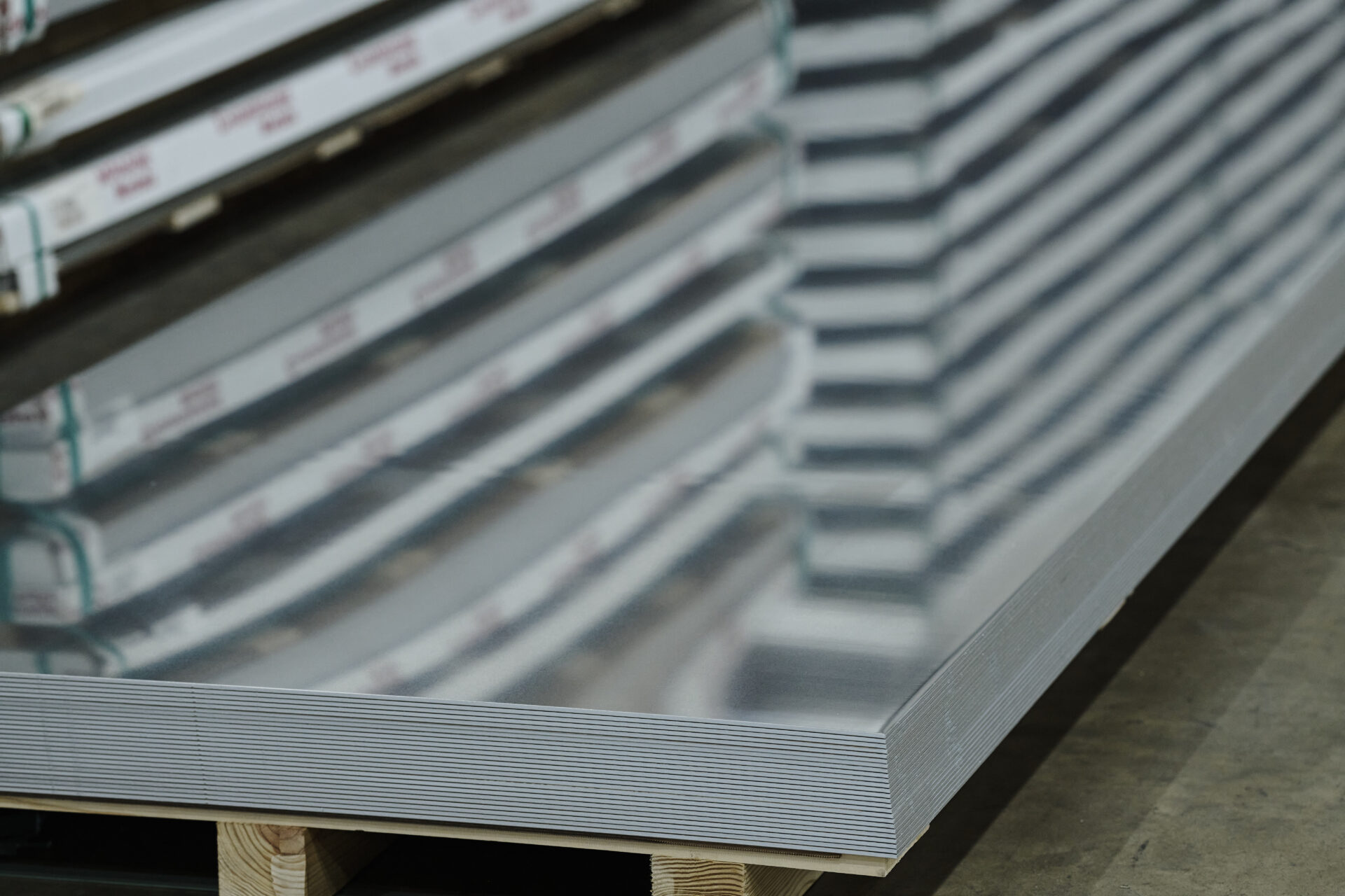 stack of unwrapped aluminum sheet reflecting other stacks of aluminum sheet